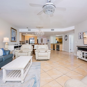 Living room features plush seating, a large TV, and a stylish chandelier, perfect for relaxation and entertainment