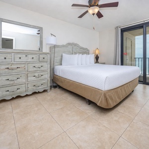 The master bedroom features a plush king bed, coastal decor, and a sliding door leading to a beautiful beach balcony