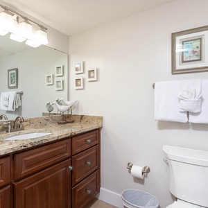 Elegant geust bathroom featuring a granite countertop, decorative accents, and a spacious mirror above the sink
