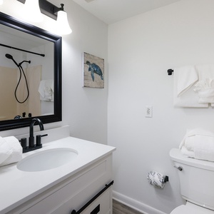 Guest bathroom featuring a stylish black-framed mirror, modern fixtures, and plush white towels
