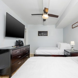 This bedroom features two comfortable beds, a large TV, and a welcoming atmosphere, perfect for relaxation