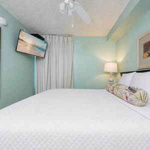 Experience restful nights in this serene bedroom, featuring a plush king bed, soft aqua walls, and a TV for entertainment