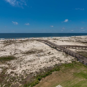 This view showcases a beautiful beach path leading to soft white sands and a serene blue sea, perfect for relaxation