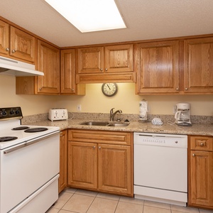Wood cabinetry complements the granite countertops in this kitchen, featuring essential appliances and a coffee maker