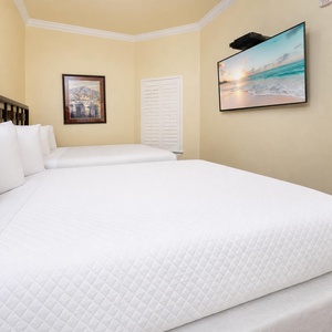 Relaxing guest bedroom featuring two plush queen beds and a wall-mounted TV, perfect for relaxation after a day of fun
