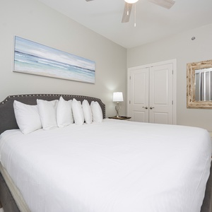 Inviting guest bedroom featuring a large king bed with multiple pillows, stylish decor, and a cozy bedside lamp