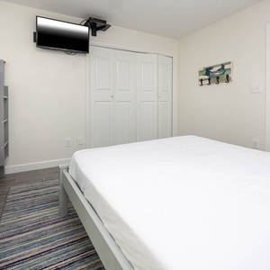 Cozy guest bedroom featuring a twin bunk bed, a queen bed, and a wall-mounted TV for relaxing evenings