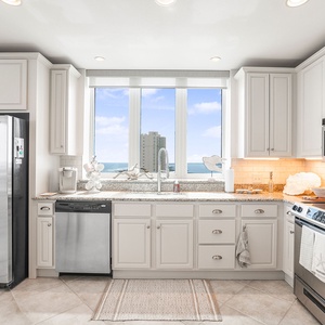 The kitchen features an elegant and spacious design with a stunning beach view through large windows