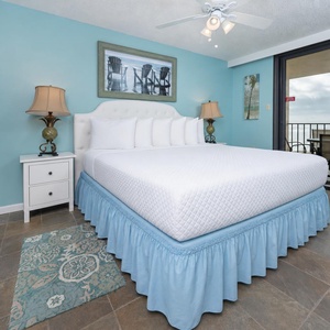 Turquoise walls complement the master suite, while sliding glass doors reveal the balcony with a serene beach front view
