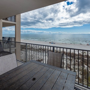 Relax at the outdoor table while enjoying the stunning views of the water and beach from your balcony