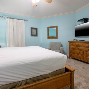 Tranquil master bedroom featuring a king bed, soft carpet, and a cozy chair for relaxation
