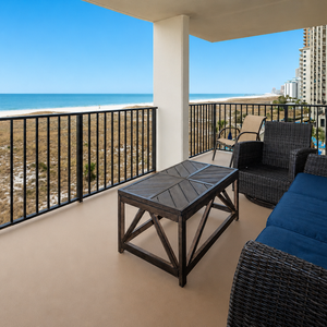 Spacious balcony features comfortable seating with a view of the beach, perfect for relaxing and enjoying the coastal breeze