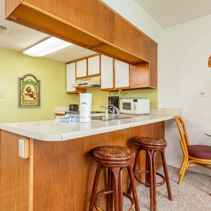 This kitchen features wooden cabinetry, a breakfast bar with stools, and a cozy dining area with a lovely floral centerpiece