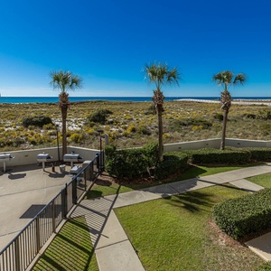 Gulf views and lush greenery create a serene outdoor space with seating and grills, perfect for relaxation and gatherings