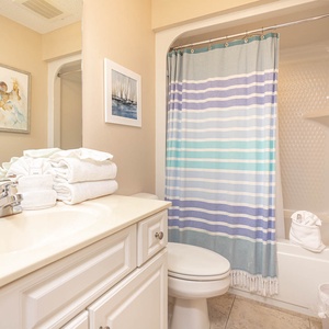 Refresh in this guest bathroom featuring a clean design, ample towels, and a shower with a striped curtain for a relaxing