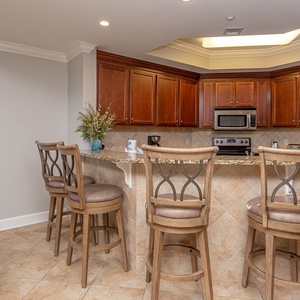 This kitchen features rich wood cabinetry, stainless appliances, and a cozy breakfast bar for a delightful cooking experience