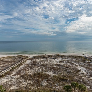 Gaze at the tranquil shoreline with gentle waves and a wooden path leading to the beach, inviting you to explore