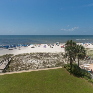 This vibrant beachfront view showcases colorful umbrellas on the sand, inviting guests to relax by the sparkling pool