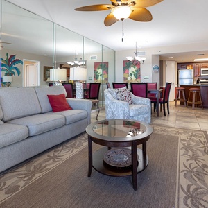 Living area features a comfortable gray sofa, stylish chairs, and a dining space with colorful artwork and a breakfast bar