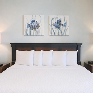 Tranquil master suite featuring a plush king bed, decorative pillows, and fish-themed artwork