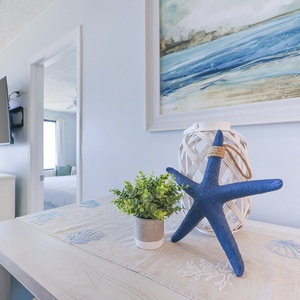 This inviting living area features a TV, beach-themed decor, and a view of the balcony, perfect for relaxation
