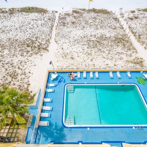 A refreshing pool area features lounge chairs and a view of the sandy beach, perfect for relaxation and fun in the sun