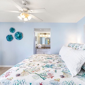 Brightly decorated master bedroom features a king bed with colorful linens and a TV on a stylish white dresser
