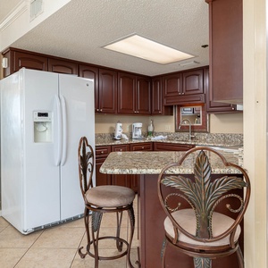 The well-appointed kitchen features rich wood cabinetry, a granite breakfast bar with stylish seating, and modern appliances