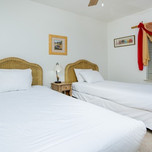 This bright guest room features two twin beds with wicker headboards, offering a comfortable space for restful nights