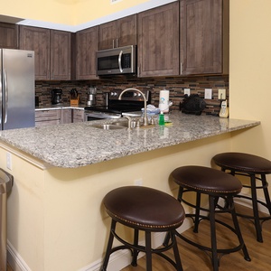 This kitchen features sleek stainless appliances, granite countertops, and a cozy breakfast bar for casual dining