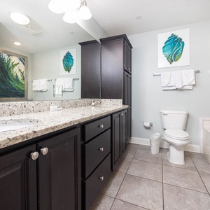 Stylish master bathroom featuring a spacious vanity, modern fixtures, and vibrant coastal artwork