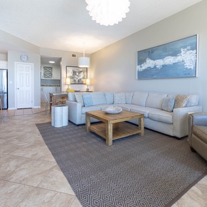 Relax in the spacious living area, featuring a comfortable sectional sofa, stylish decor, and a wooden coffee table