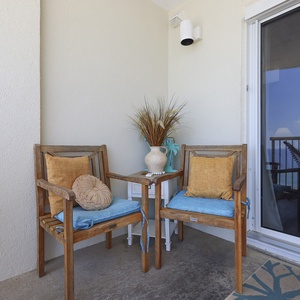 Enjoy a relaxing view from the balcony with two wooden chairs, vibrant cushions, and a decorative vase, perfect for unwinding