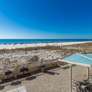 Enjoy the outdoor seating area with grills and tables, perfect for gatherings while taking in the beach views