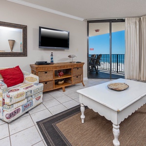 Relax in the inviting living area, featuring colorful seating and a view of the beach through expansive sliding doors
