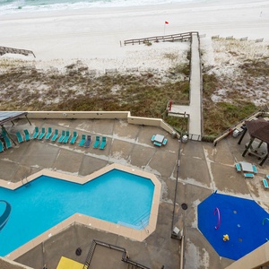 This vibrant pool area features turquoise loungers, a splash pad for kids, and easy beach access for endless fun
