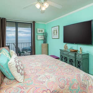 Master bedroom featuring a cozy king bed, plush pillows, and a balcony with a serene coastal view