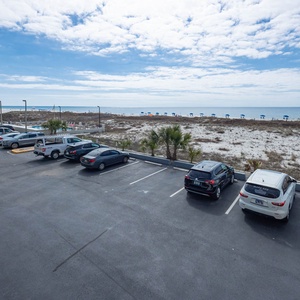 This view showcases a serene beachfront with umbrellas lining the shore, framed by parked vehicles in the foreground