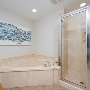 Indulge in relaxation with a jetted tub and a spacious walk-in shower, accented by coastal artwork for a serene atmosphere