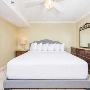 The bedroom features a queen bed with plush pillows, a stylish dresser, and an adjoining bathroom with a tub/shower combo