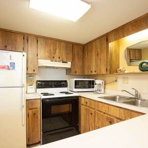 This kitchen features wooden cabinetry, essential appliances, and a convenient layout for meal preparation