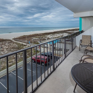 Enjoy the beachfront view from this inviting balcony, perfect for relaxation with comfortable seating and a table