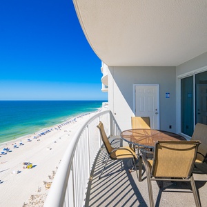 Metal chairs surround the round balcony table as you enjoy calming views of the shore and bright blue sky