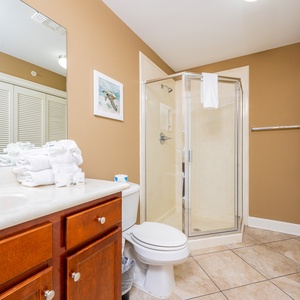 The extra bath features a stylish shower, elegant cabinetry, neatly arranged towels, and laundry area with a washer and dryer