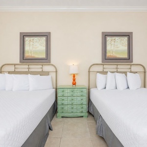 Guest bedroom featuring two cozy queen beds, a charming green nightstand, and serene nature artwork