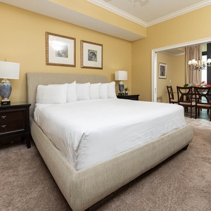 Welcoming master bedroom featuring a king bed, cozy armchair, and warm yellow walls for a relaxing stay