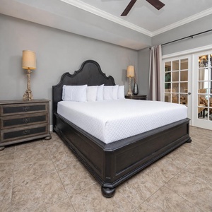 The master bedroom features a plush king bed, elegant decor, and a lovely view through glass doors leading to the dining area
