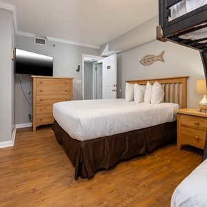 Guest bedroom featuring a queen bed, a full over full bunk bed, flat-screen TV, and warm wood accents for a relaxing retreat