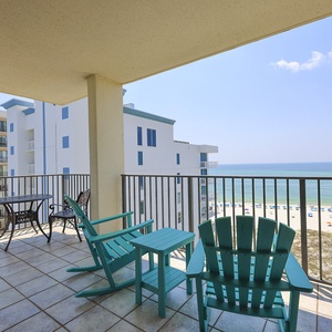 Relax on the balcony with turquoise chairs, enjoying views of the beach and gentle waves lapping against the shore