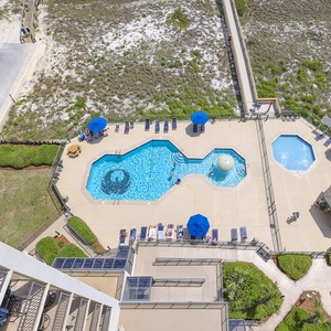 Aerial view of the pool area featuring a large octagonal pool, lounge chairs, and shaded seating under blue umbrellas